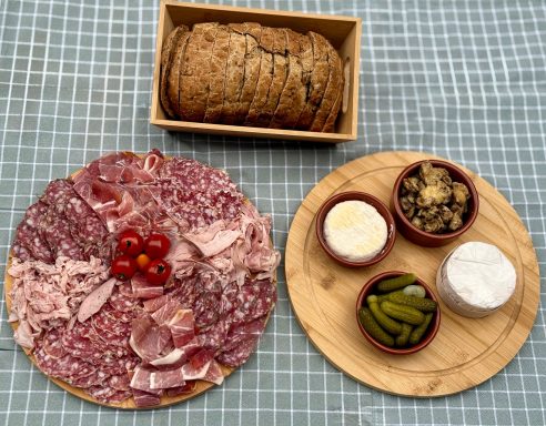 Planche apéritive maison au pain artisanal et produits locaux Assortiment de charcuterie, cornichons, condiments et pain dans un cadre rustique.