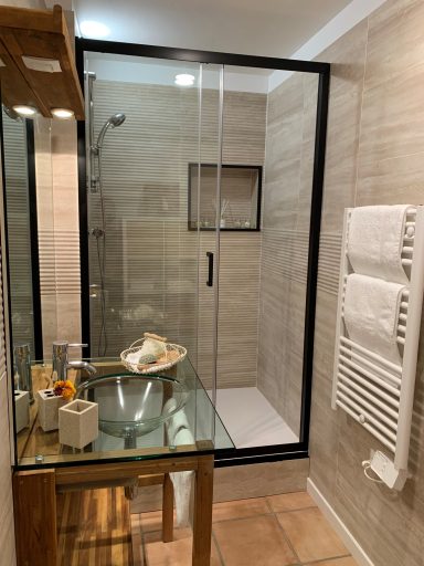 Salle de bains moderne avec douche en verre, lavabo en verre et serviettes blanches.