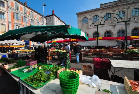 Marché de Vienne : produits locaux pour nos planches apéritives Marché animée avec des étals de fruits et légumes sous des parasols verts.