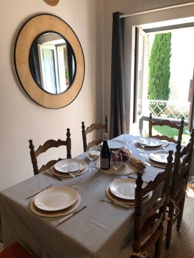 Table dressée pour le dîner avec assiettes blanches et miroir rond au mur.