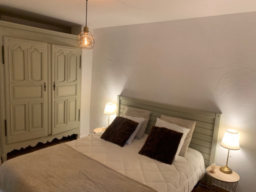 Chambre cozy avec un lit double, deux lampes de chevet et un armoire en bois.