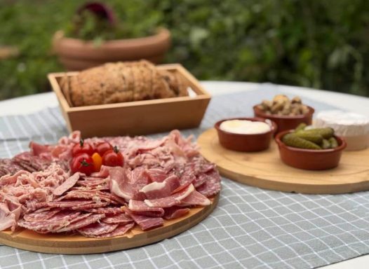 Planche apéritive de saison avec fromages, fruits et légumes frais Plate de charcuterie avec jambon, tomates cerises, pain et accompagnements en pots.