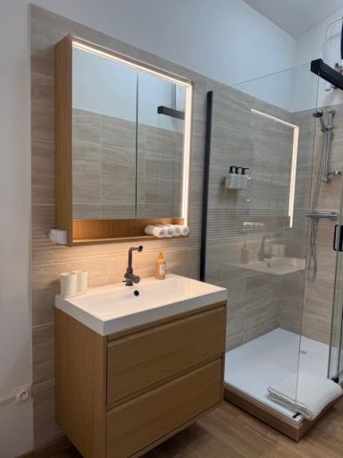 Salle de bain moderne avec meuble vasque en bois et douche en verre.