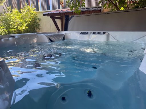 Bain à remous extérieure avec eau claire et bulles, entouré de verdure.