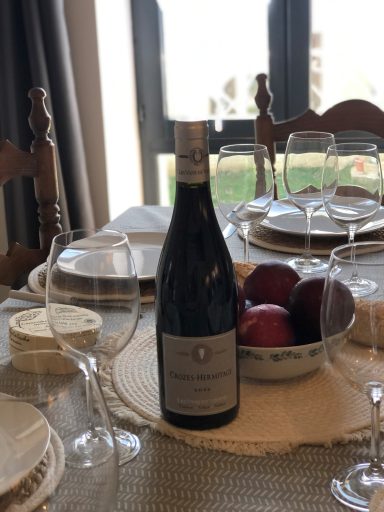 Bouteille de vin sur une table dressée avec des verres et des pommes.