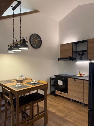 Cuisine moderne avec mange-debout, chaises, et électroménagers en bois et noir